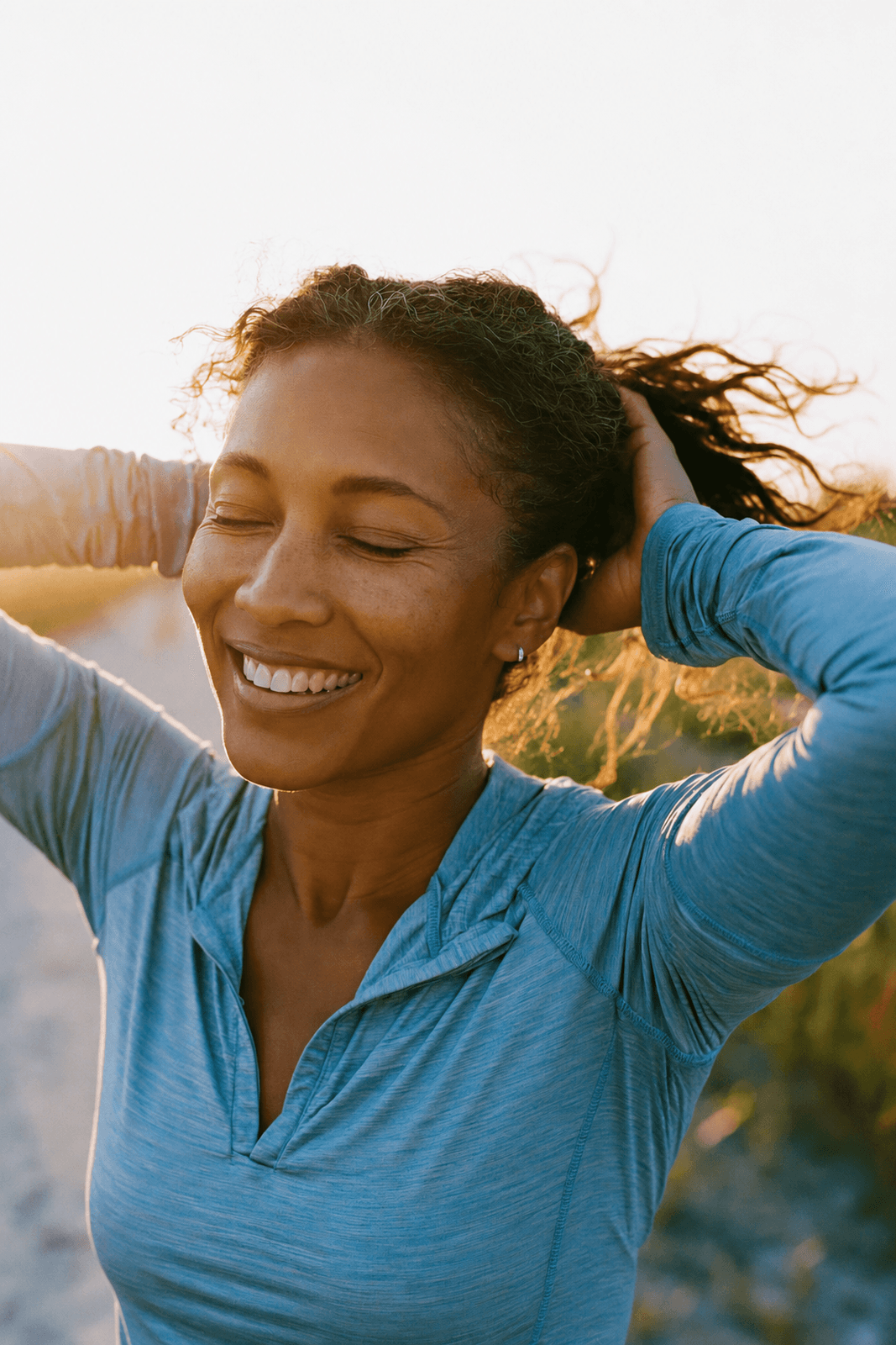 Teledris patient tying her hair back, feeling confident after a workout